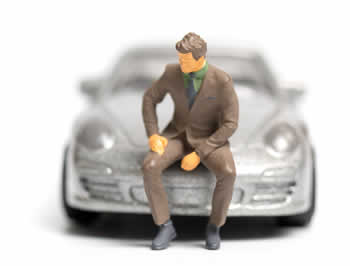 Imagine ce reprezinta o masina in miniatura cu barbat asezat pe capota